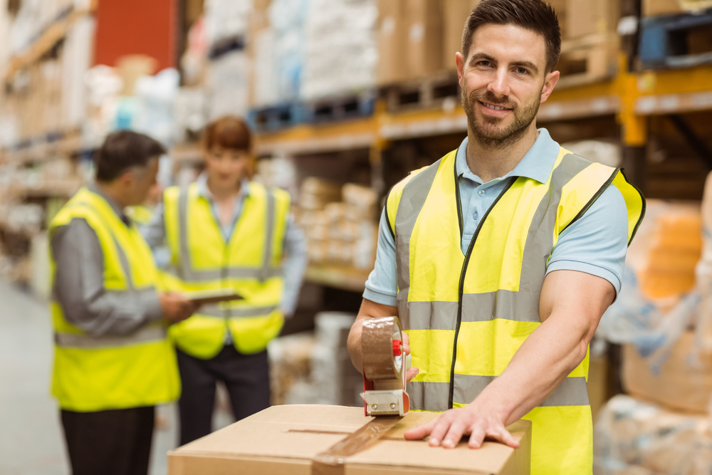 Smiling warehouse workers preparing a shipment in a large warehouse Smiling warehouse workers preparing a shipment in a large warehouse